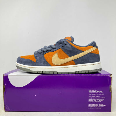 Nike SB Dunk Low sneaker in navy suede with orange panels, a pale yellow side swoosh, and a white midsole.