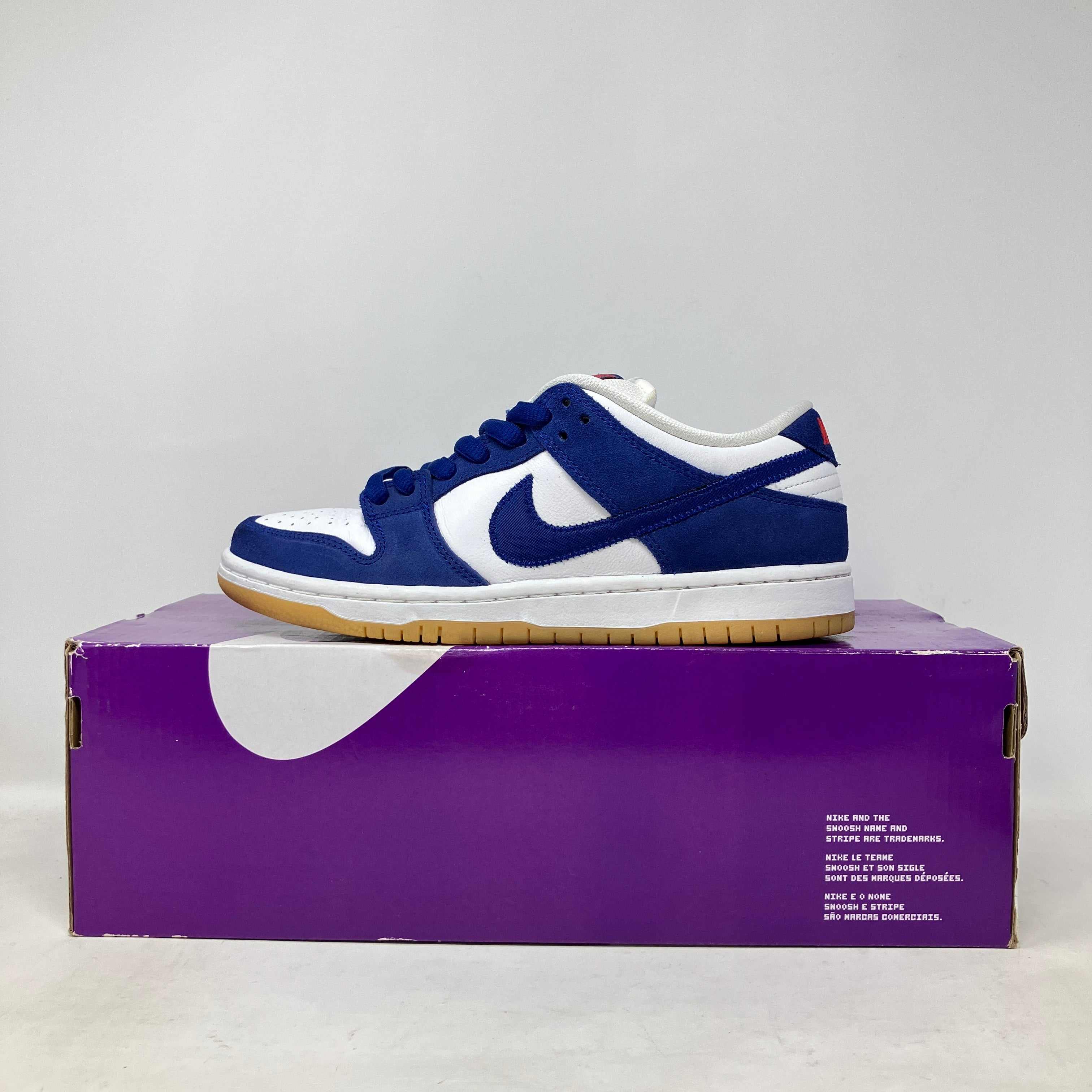 Nike SB Dunk Low Los Angeles Dodgers blue and white sneaker on purple box, pre-owned with all accessories.