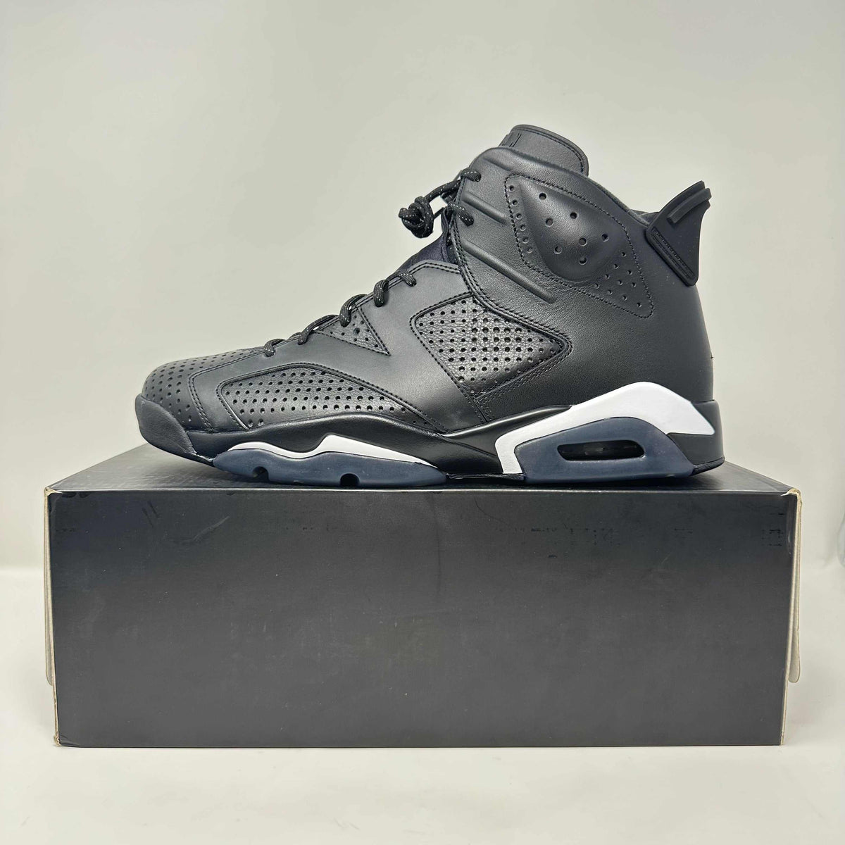 Jordan 6 Retro basketball shoe in all black leather with perforated panels and white midsole accents on a black box.