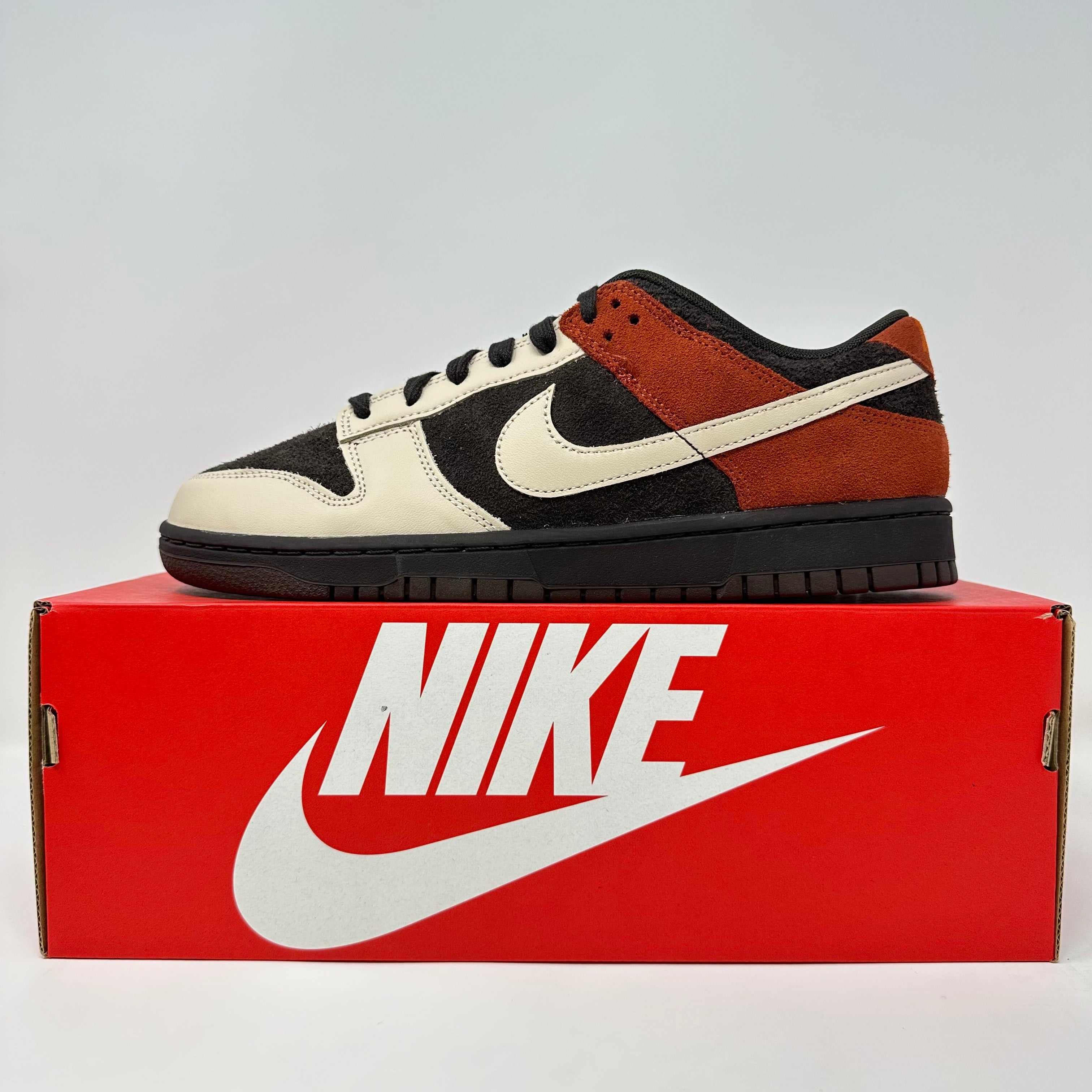 Nike Dunk Low Red Panda sneaker in black, cream, and red suede on a red Nike box.