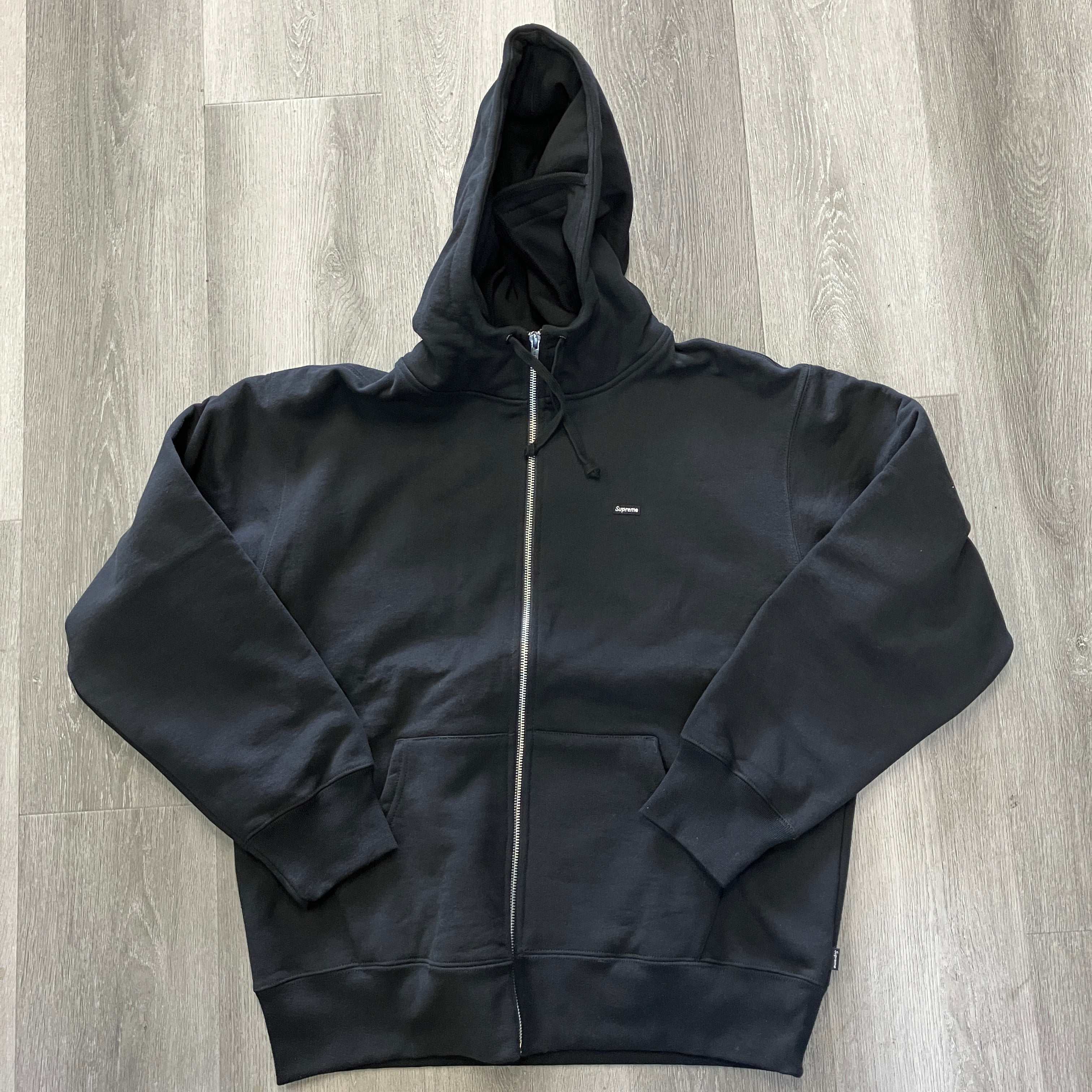 Supreme Small Box Facemask black zip up hooded sweatshirt flat lay on wooden floor