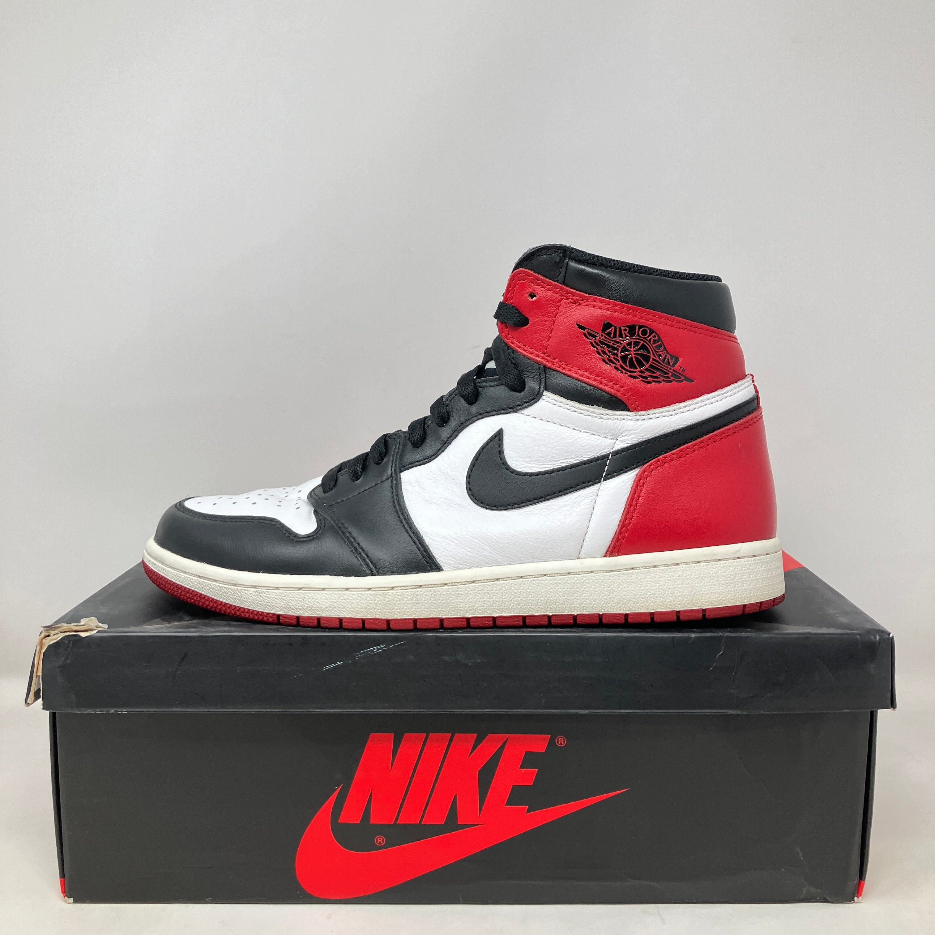 Jordan 1 Retro Black Toe (2016) sneaker in black, white, and red on Nike box, pre-owned condition without extra laces