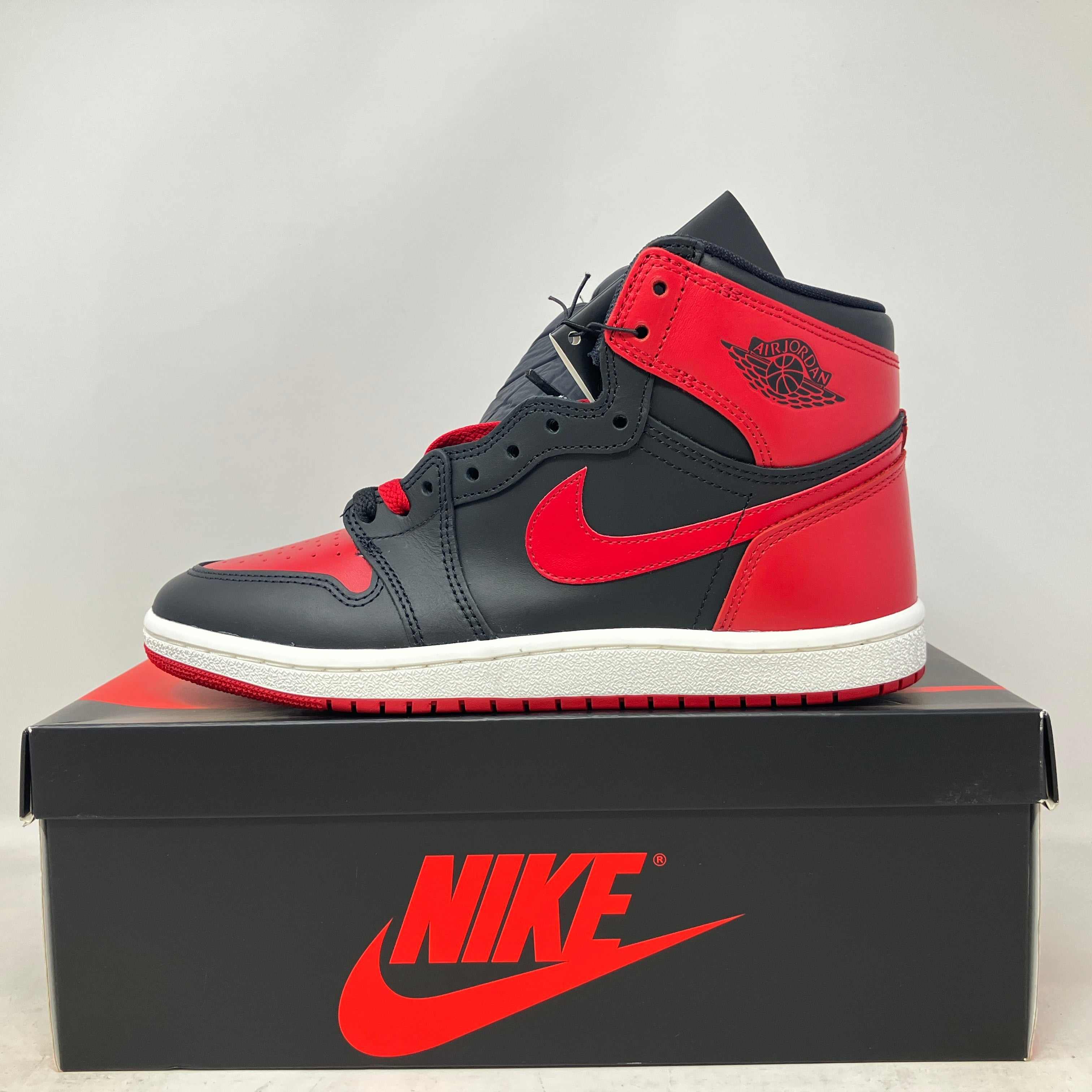 Jordan 1 Retro High '85 OG Bred sneaker in black and red on Nike box, brand new with accessories included