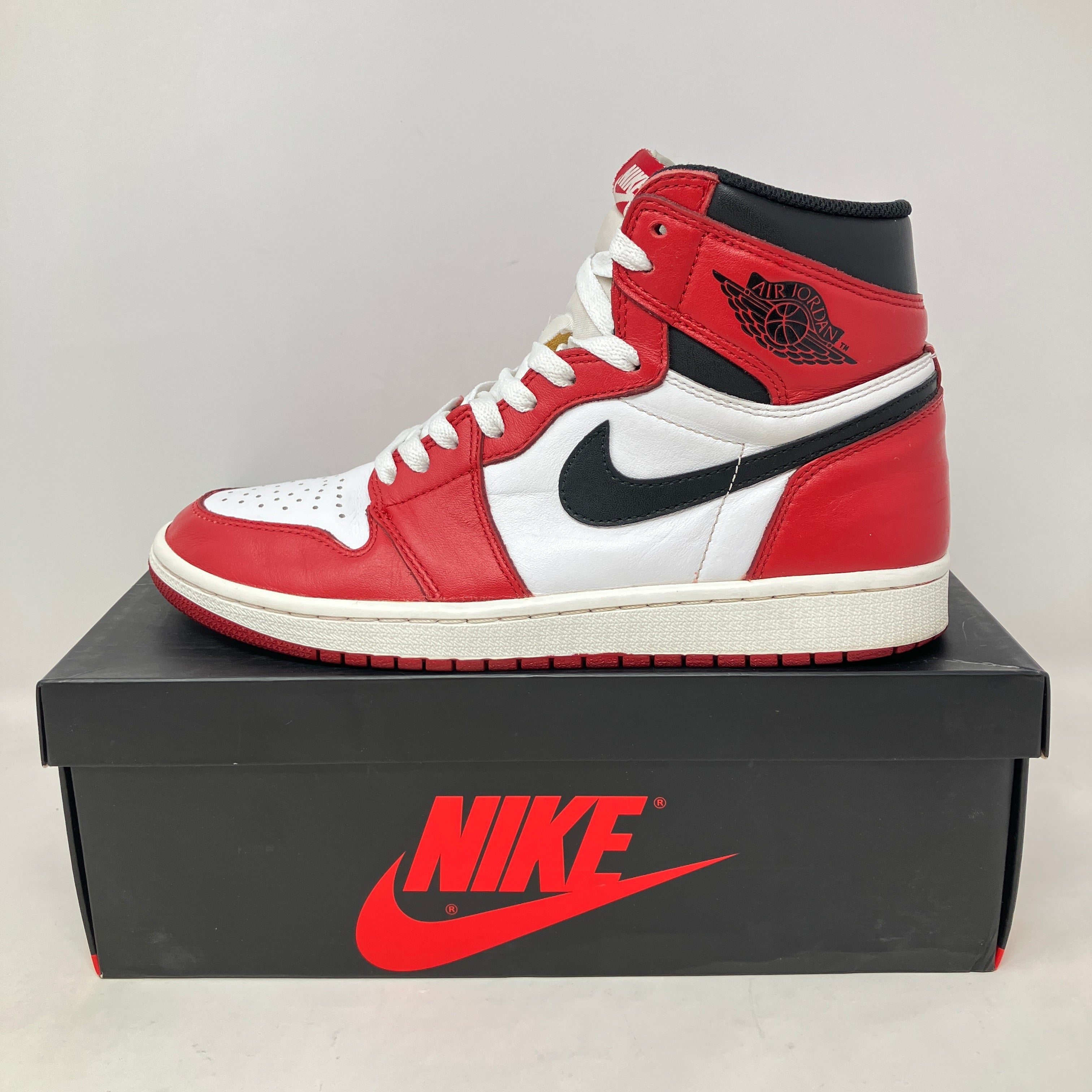 Pre-owned Jordan 1 Retro Chicago 2015 sneaker with original accessories, missing extra laces, displayed on Nike shoebox.