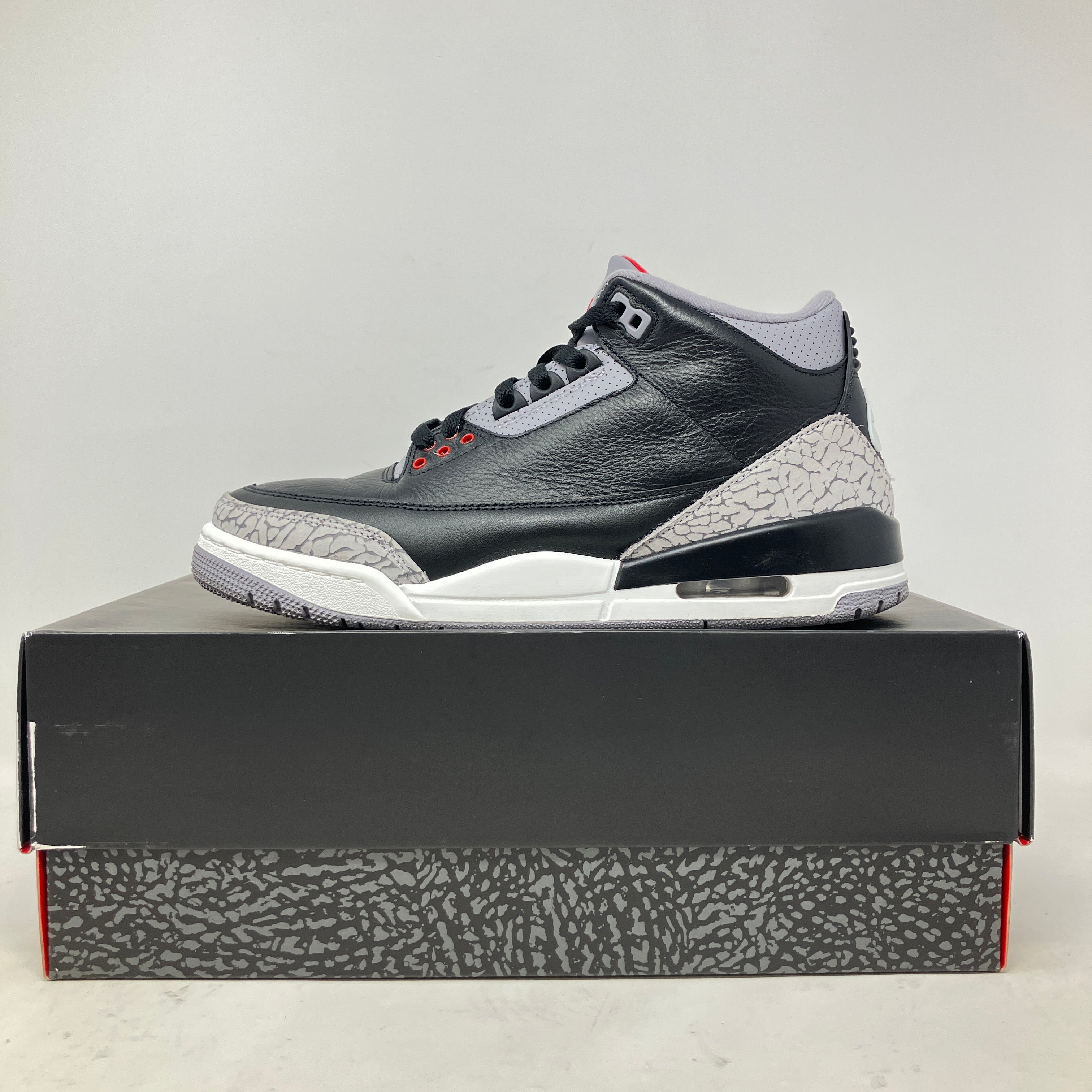 Side view of pre-owned Jordan 3 Retro OG Black Cement 2024 sneaker on box with accessories included
