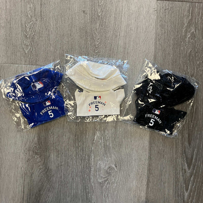 Set of black, blue, and white Freddie Freeman Labubu Dodger jerseys in packaging on wooden floor