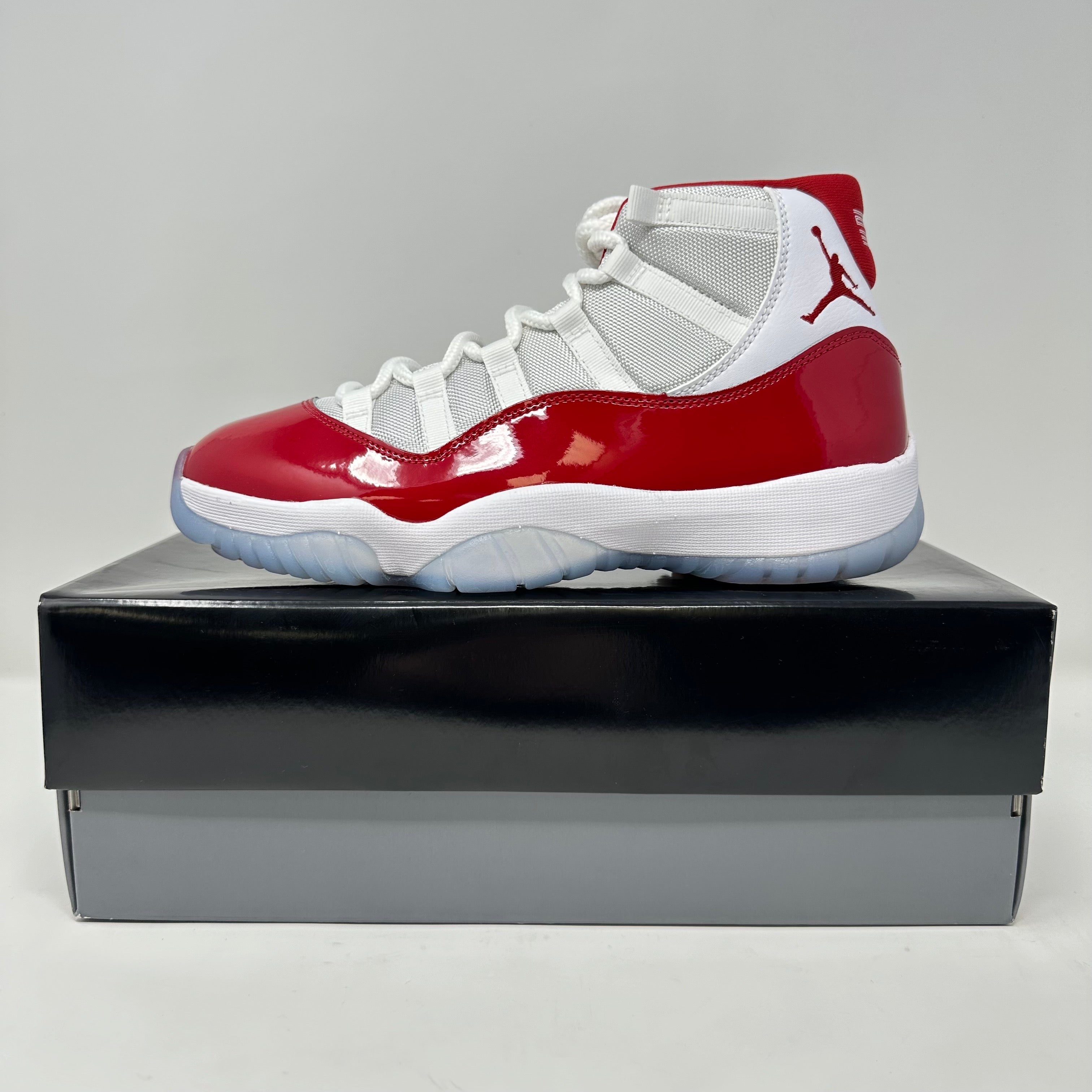 Jordan 11 Retro Cherry 2022 sneaker in white and red on black shoe box, brand new with accessories included