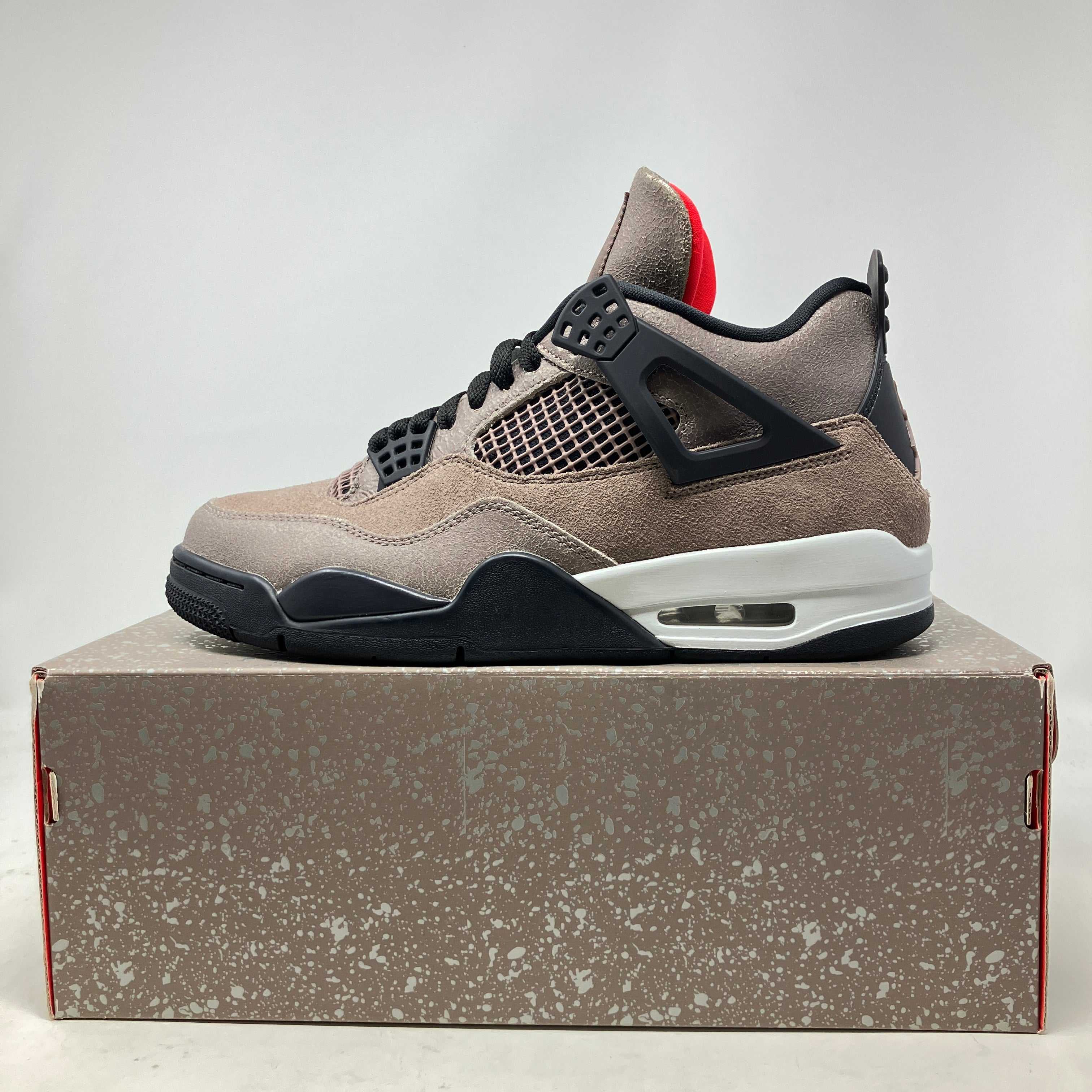 Side view of pre-owned Jordan 4 Retro Taupe Haze sneaker with all accessories on speckled shoebox