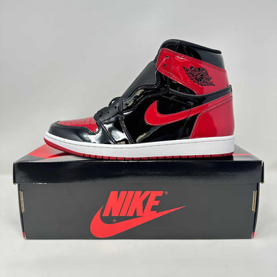 Jordan 1 Retro High OG high-top sneaker in glossy black and red patent leather, with Swoosh and white midsole.