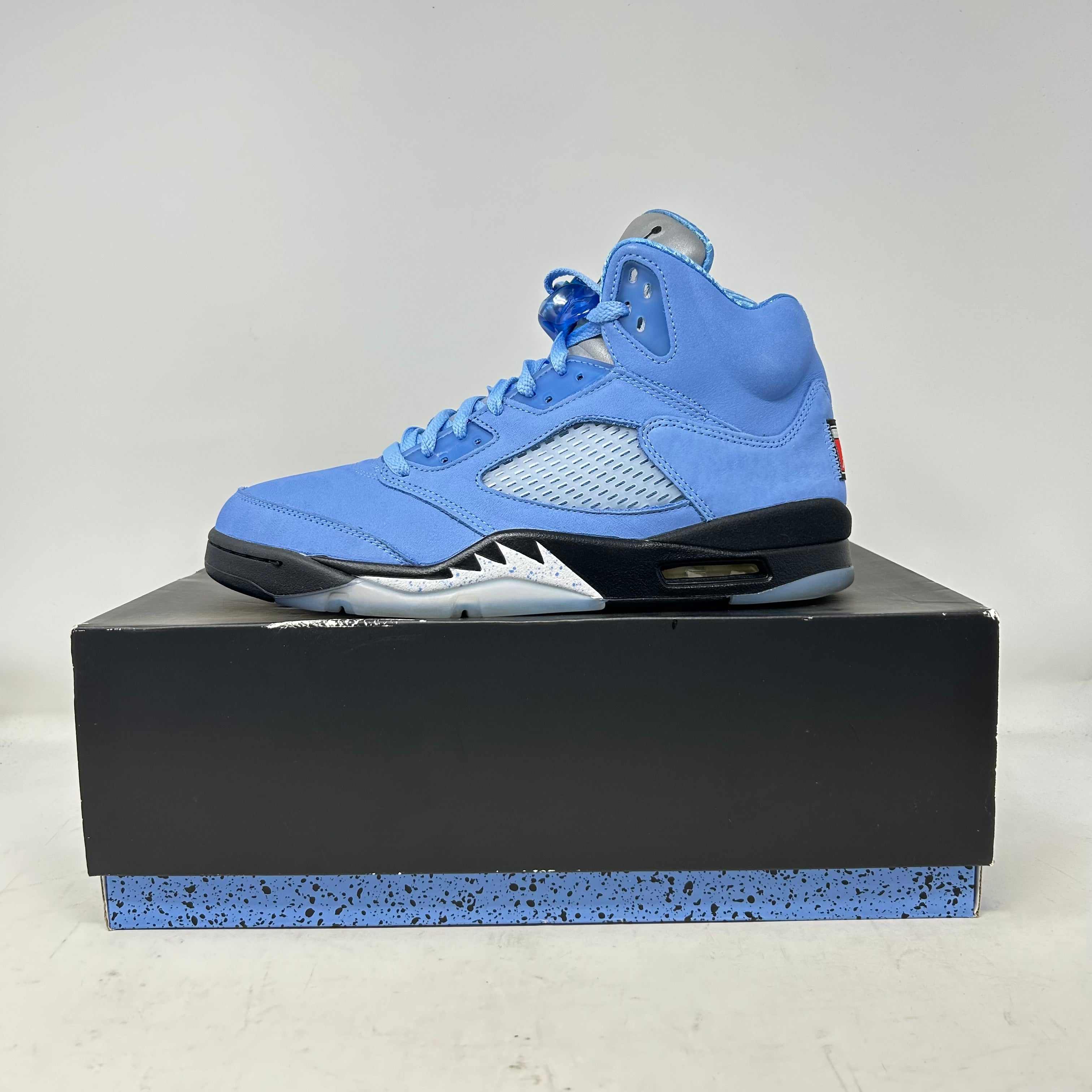 Jordan 5 Retro UNC University Blue sneaker on black and blue speckled box, pre-owned condition with accessories included