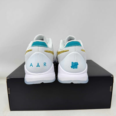 Brand new Nike Kobe 5 Protro Undefeated What If White sneakers with teal and gold accents, displayed on a replacement box.