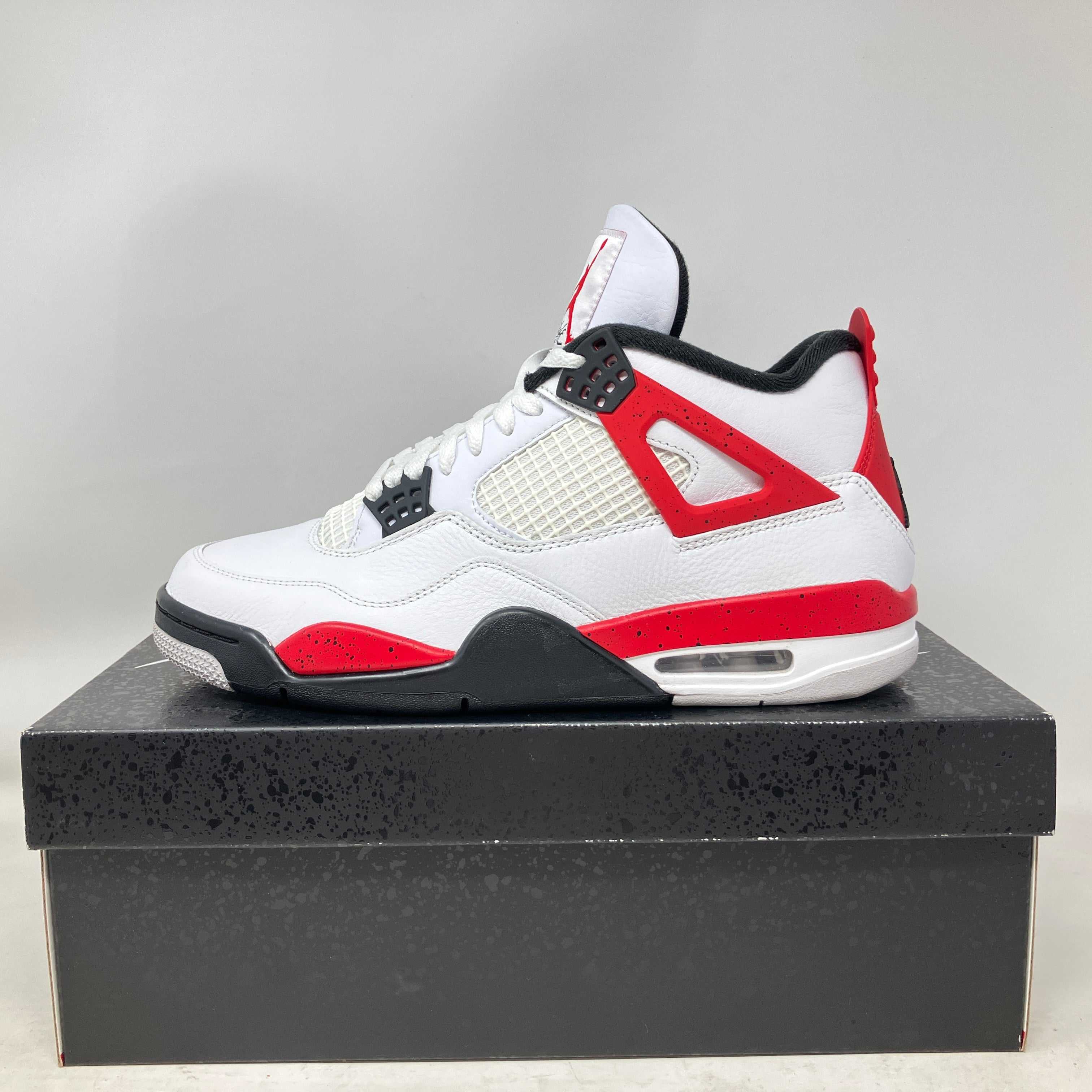 Jordan 4 Retro Red Cement sneaker in white, red, and black on shoebox, pre-owned with accessories included