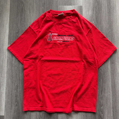 Red vintage 2002 Angels American League Champions tee on wooden floor.