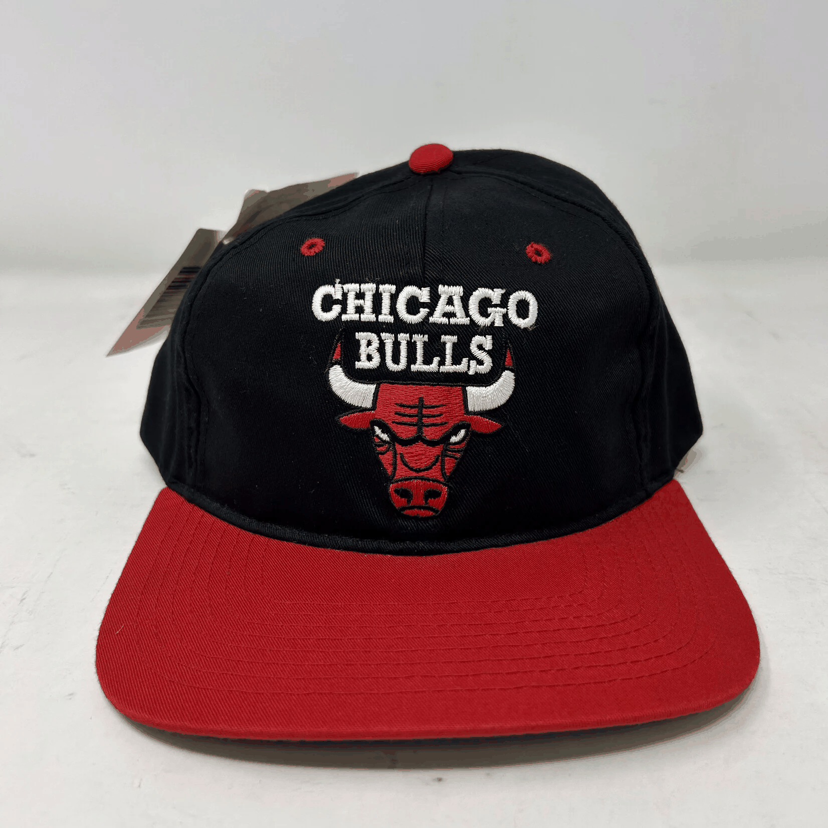 Vintage Chicago Bulls snapback hat with black crown and red brim, featuring embroidered logo and text