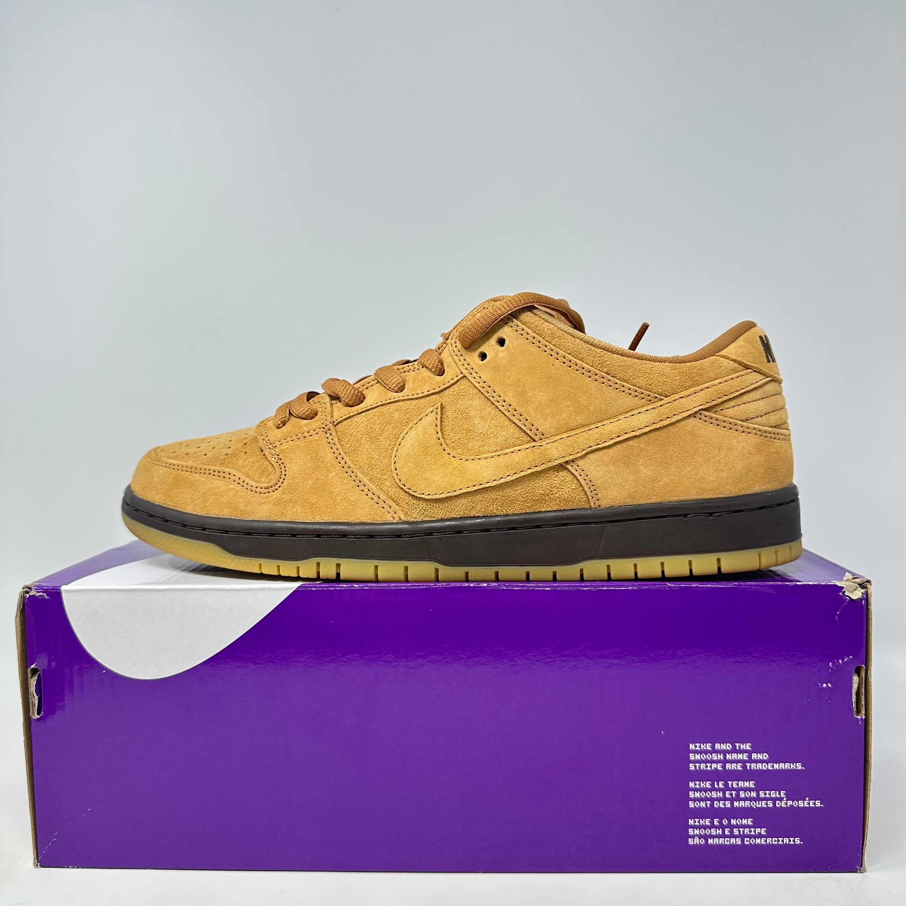 Nike SB Dunk Low Wheat sneaker in brand new condition displayed on a purple shoe box with all accessories included.