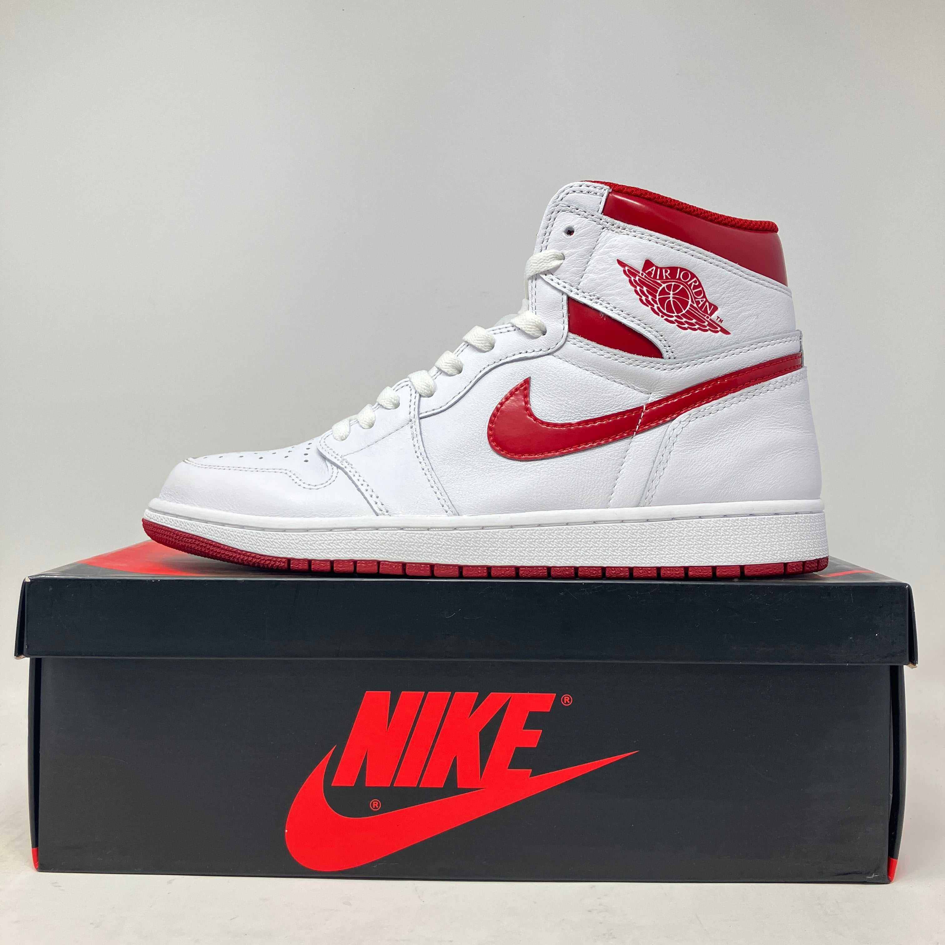 White and metallic red Jordan 1 Retro sneaker (2017) displayed on black Nike box, pre-owned condition with all accessories included