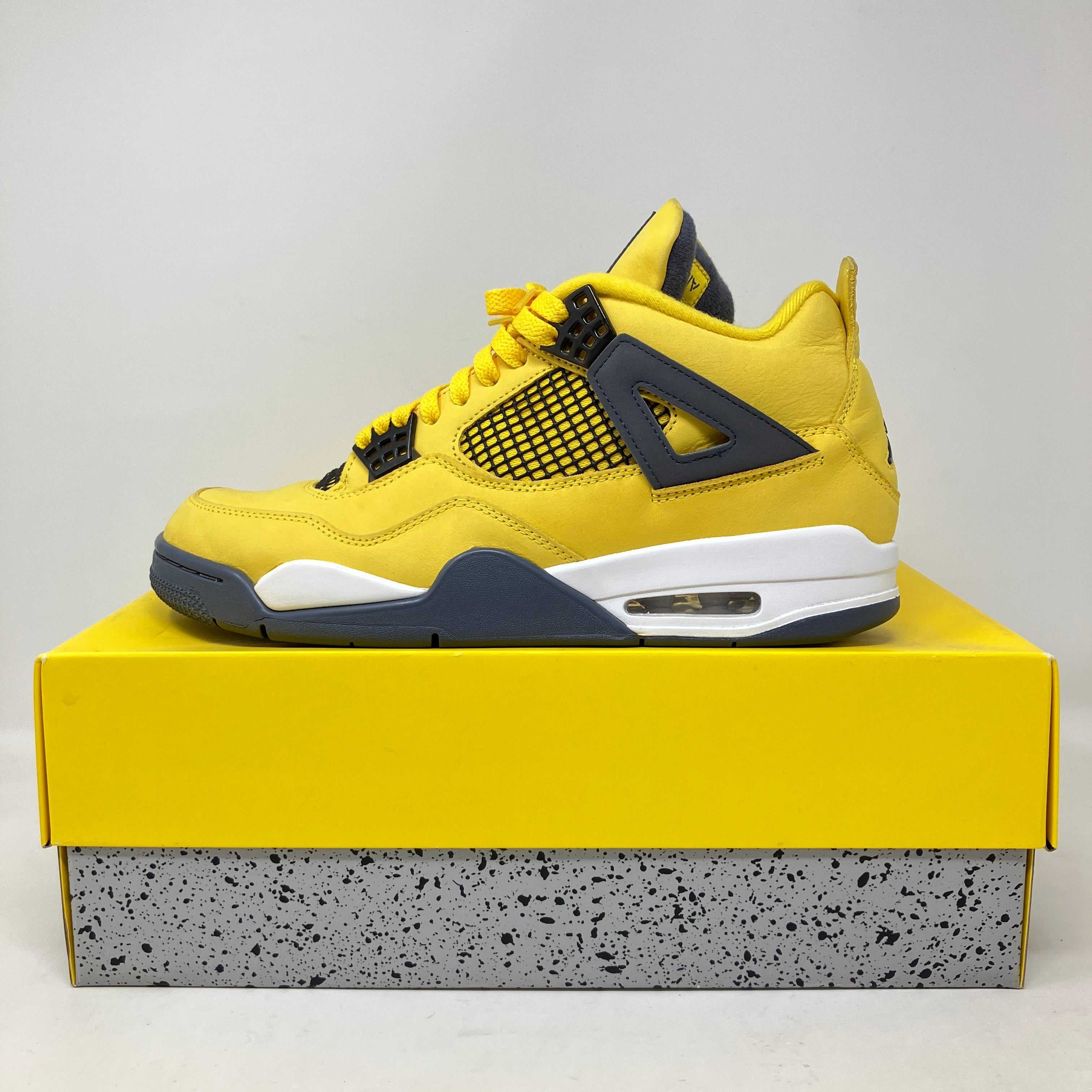 Jordan 4 Retro Lightning 2021 yellow and black sneaker on yellow and speckled gray box, pre-owned with accessories included