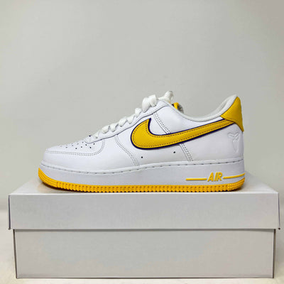 Nike Air Force 1 Low white leather sneaker with yellow accents, yellow swoosh, and perforated toe box design