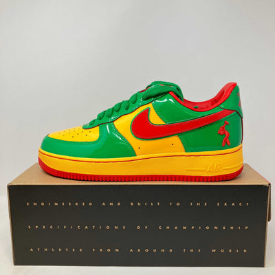 Nike Air Force 1 low-top sneaker in glossy green and yellow leather with red Swoosh, laces, and outsole.