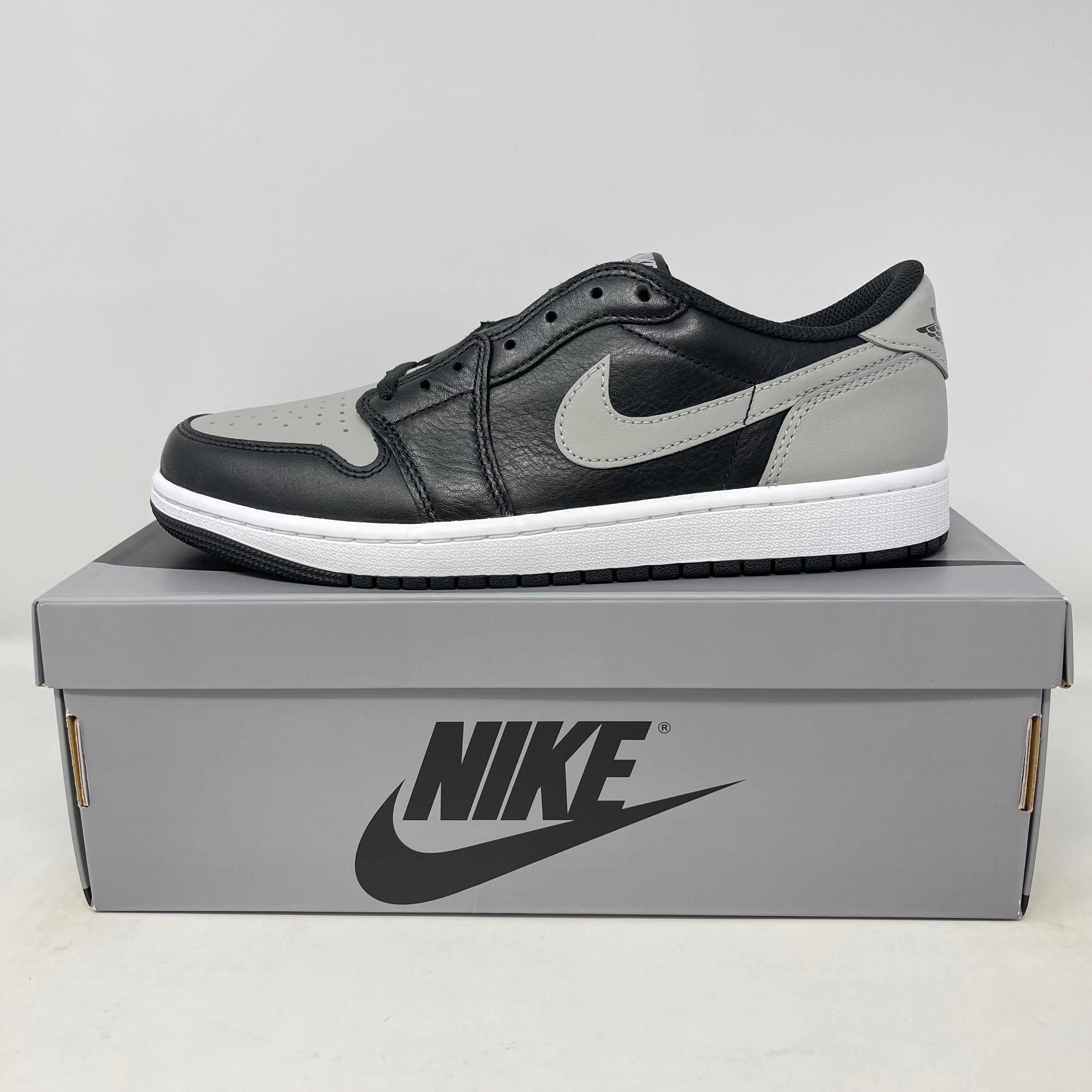 Jordan 1 Retro Low OG Shadow sneaker in black and grey on a Nike shoebox, brand new with all accessories included.