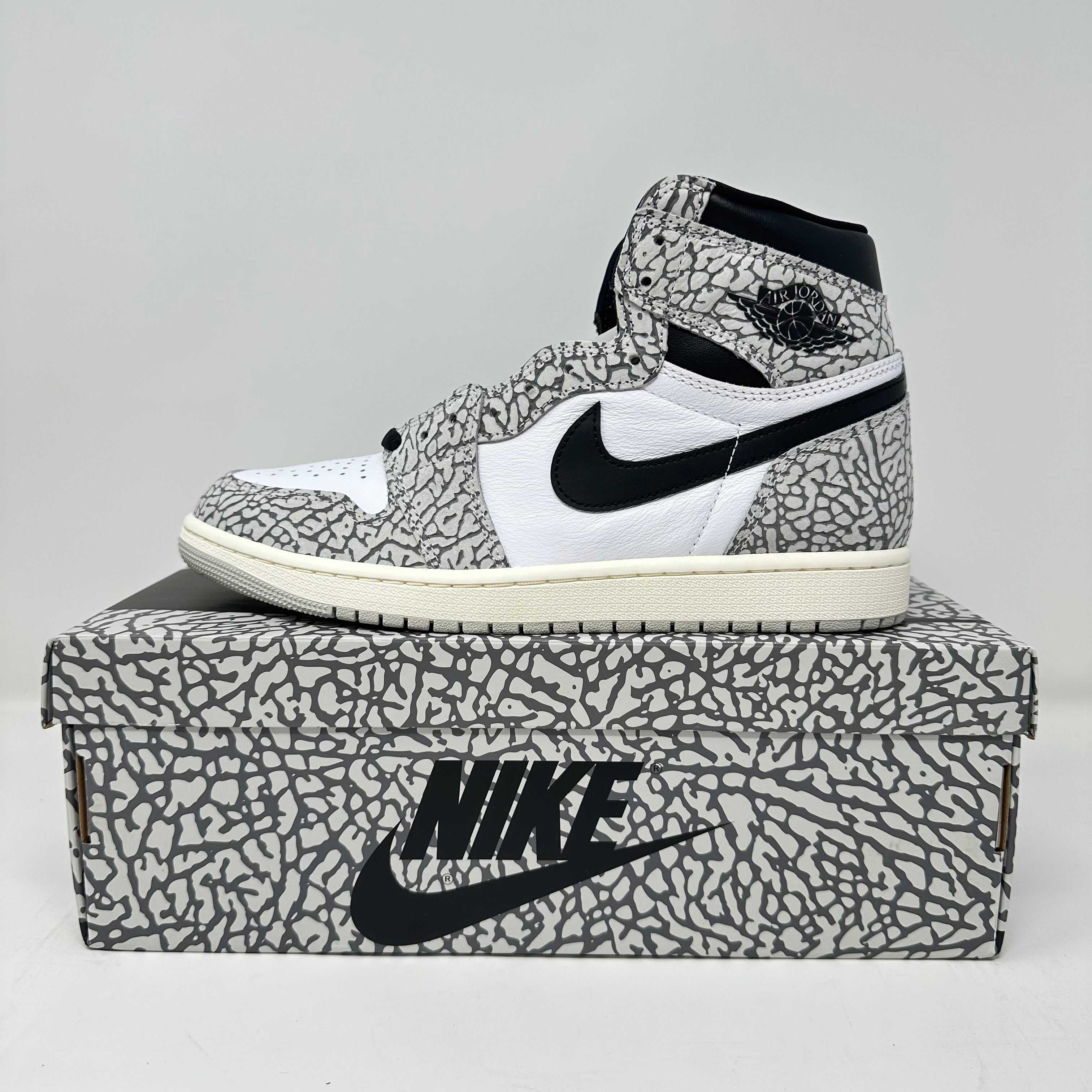Jordan 1 Retro High OG White Cement sneaker on matching Nike box, brand new with accessories included
