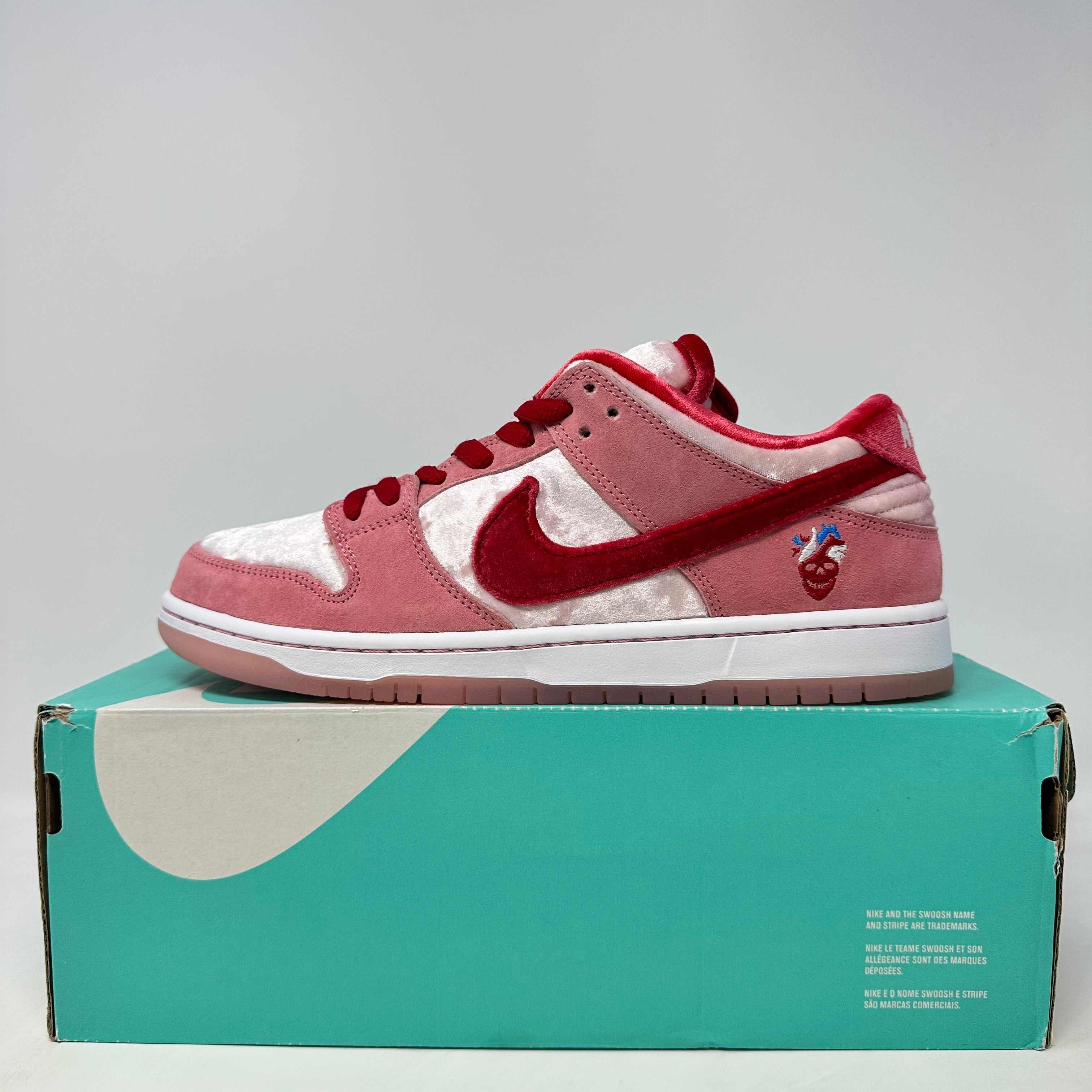 Nike SB Dunk Low StrangeLove Skateboards in pink and red on teal box, brand new with all accessories included