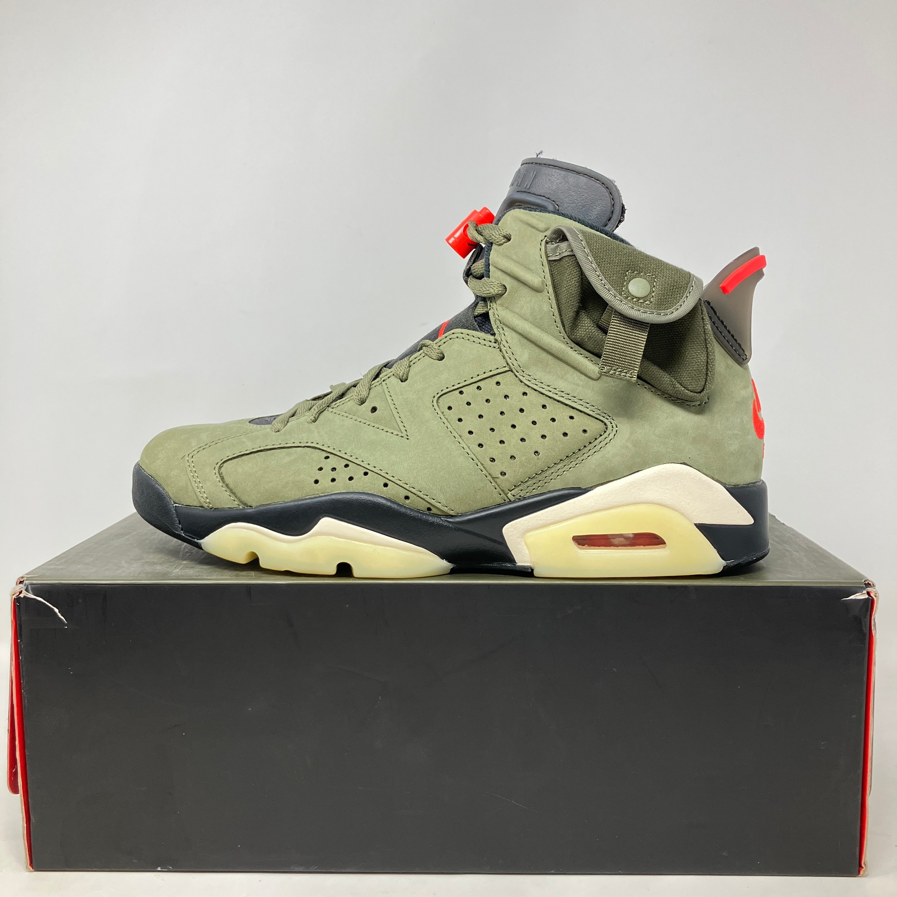 Jordan 6 Retro Travis Scott sneaker in olive green placed on a black shoebox, pre-owned with all accessories included.