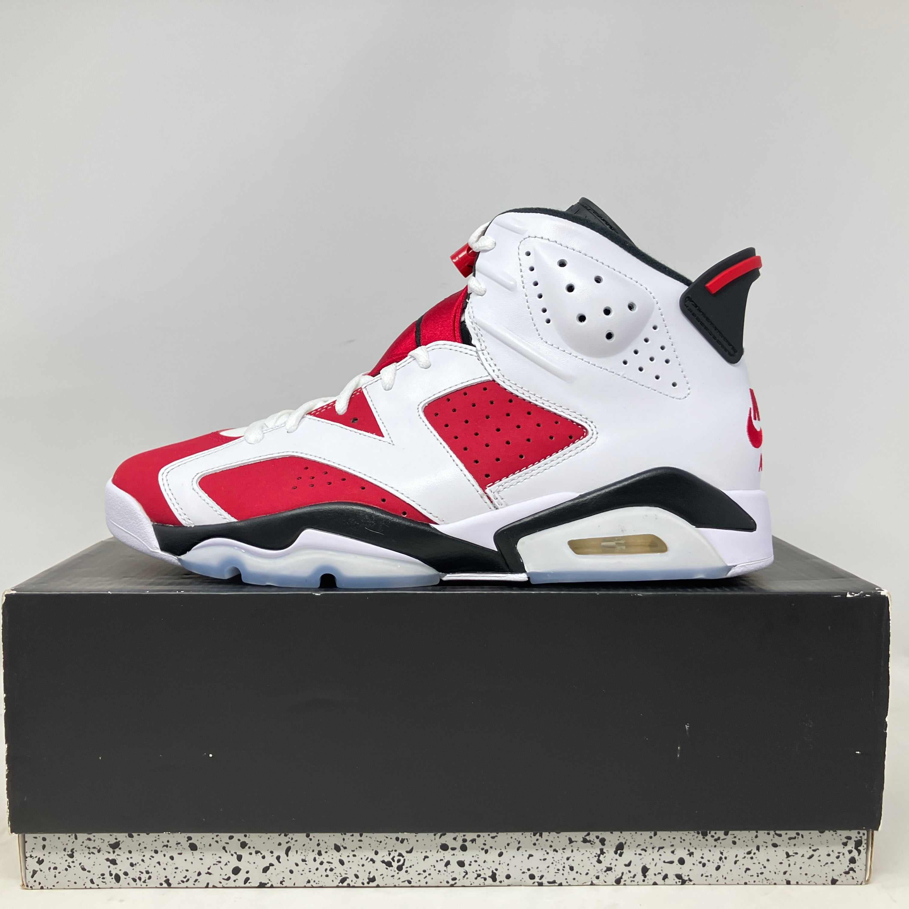Side view of brand new Jordan 6 Retro Carmine sneaker on black box with speckled sole base