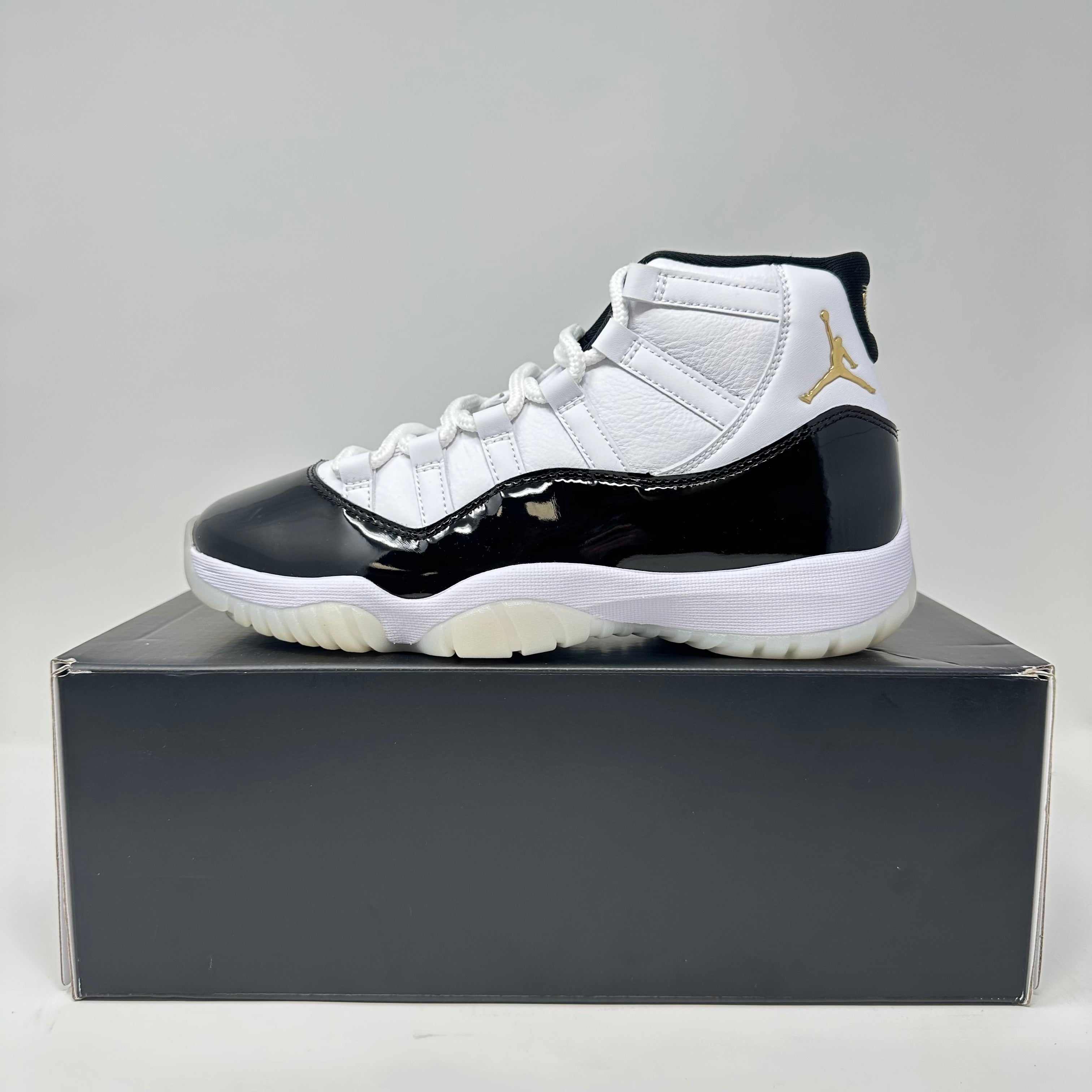 Side view of brand new Jordan 11 Retro DMP Gratitude 2023 sneaker on black box with white, black, and gold detailing