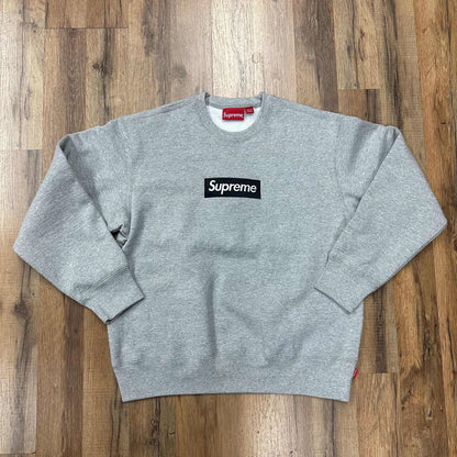 Heather grey Supreme Box logo crewneck sweatshirt laid flat on wooden floor